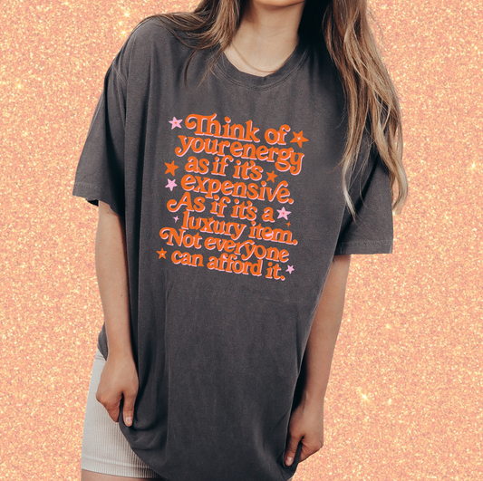 A woman wearing a gray t-shirt with a printed message about energy and luxury.