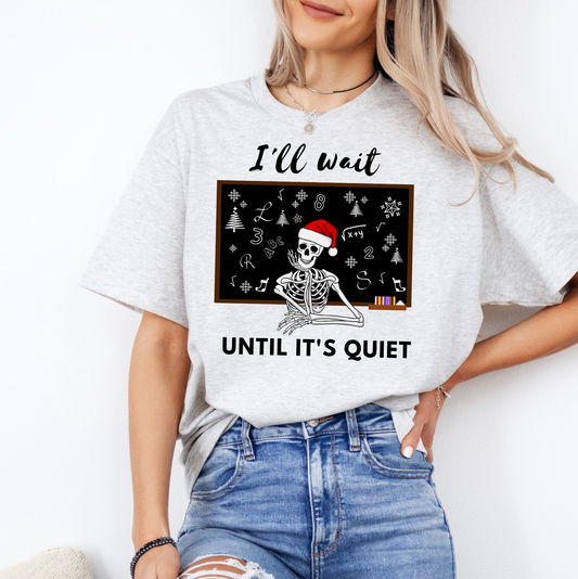A woman wearing a white t-shirt with a graphic design of a skeleton wearing a Santa hat and the text "I'll wait until it's quiet" printed on it.