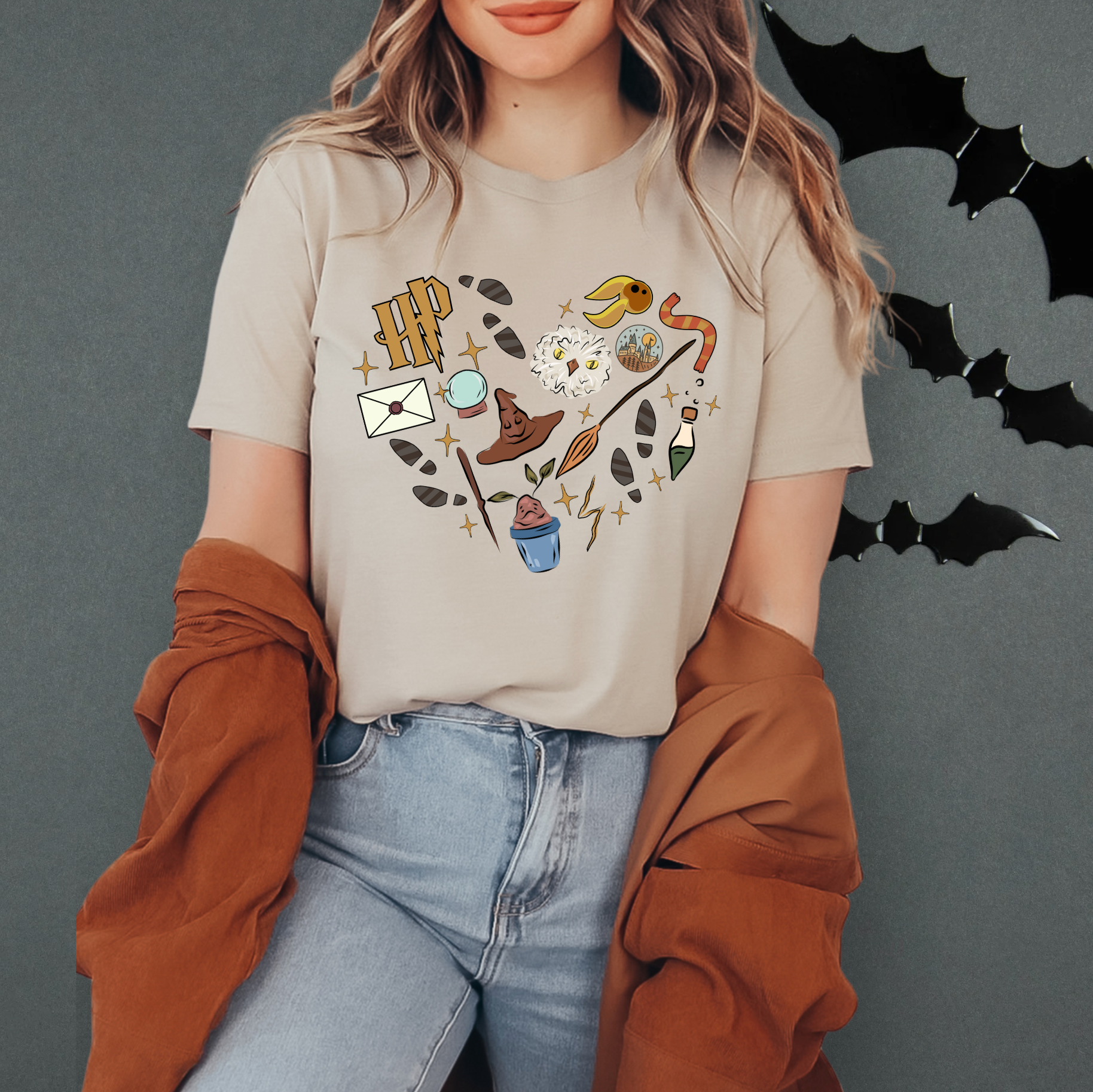 A woman wearing a t-shirt with a graphic design of various objects and symbols, including bats, a hat, and a bird, standing against a dark background.