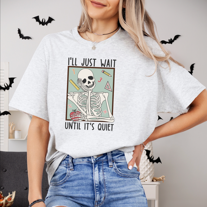 A woman wearing a white t-shirt with a graphic design of a skeleton and the text "I'll just wait until it's quiet" printed on it.