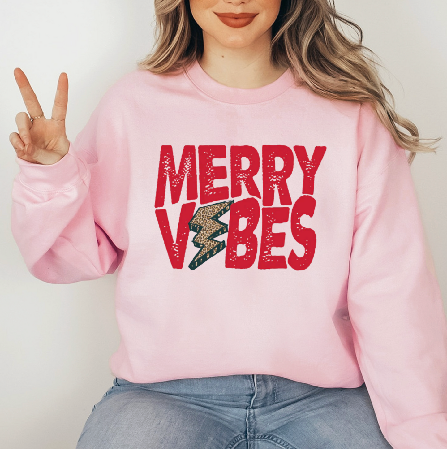 A woman wearing a pink sweatshirt with the text "MERRY VIBES" printed on it.