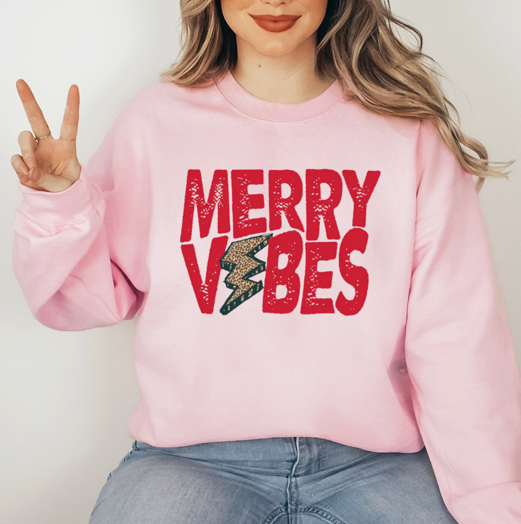 A woman wearing a pink sweatshirt with the text "MERRY VIBES" printed on it.