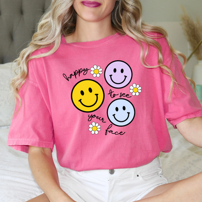 a woman sitting on a bed wearing a pink shirt with smiley faces on it