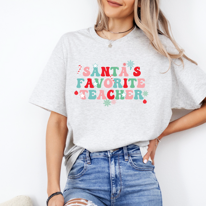 A woman wearing a gray t-shirt with the text "Santa's Favorite Teacher" printed on it.