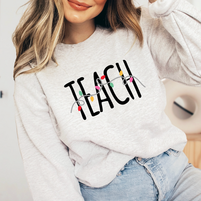 A woman wearing a white sweatshirt with the word "TEACH" printed on it.