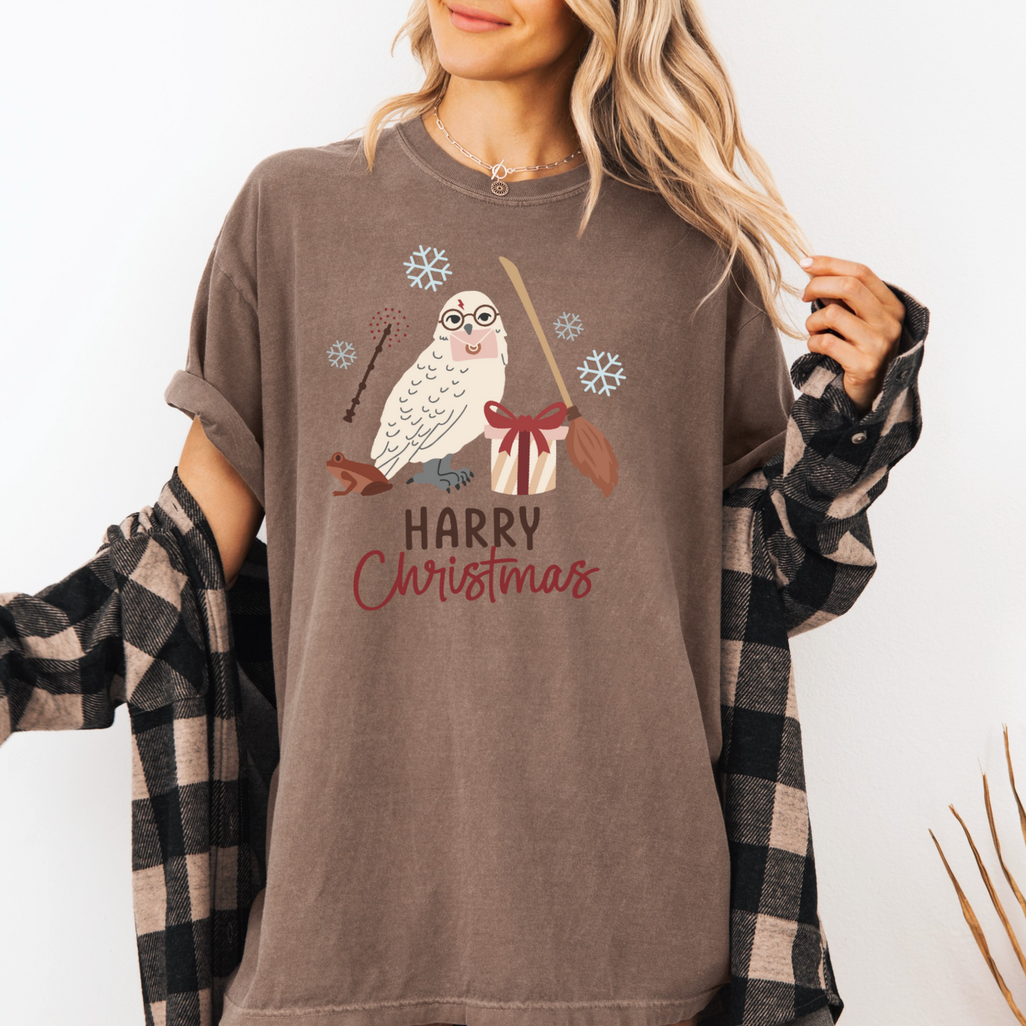 A woman wearing a brown t-shirt with a graphic of a white owl and the text "Harry Christmas" printed on it.