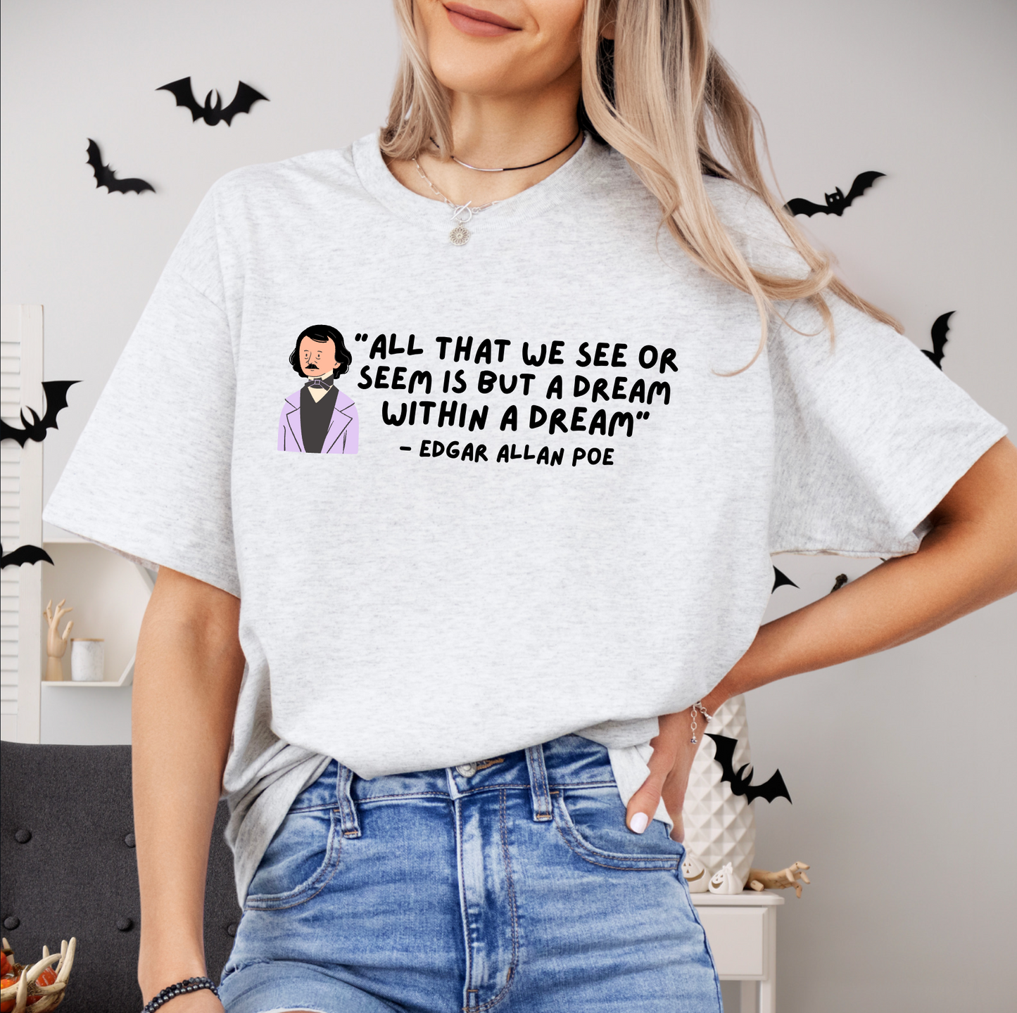 A woman wearing a white t-shirt with a quote printed on it, standing in front of a wall with bats hanging from it.