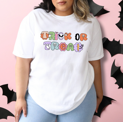 A person wearing a white t-shirt with the text "TRICK OR TREAT" printed on it, standing in front of a pink background with black bats.