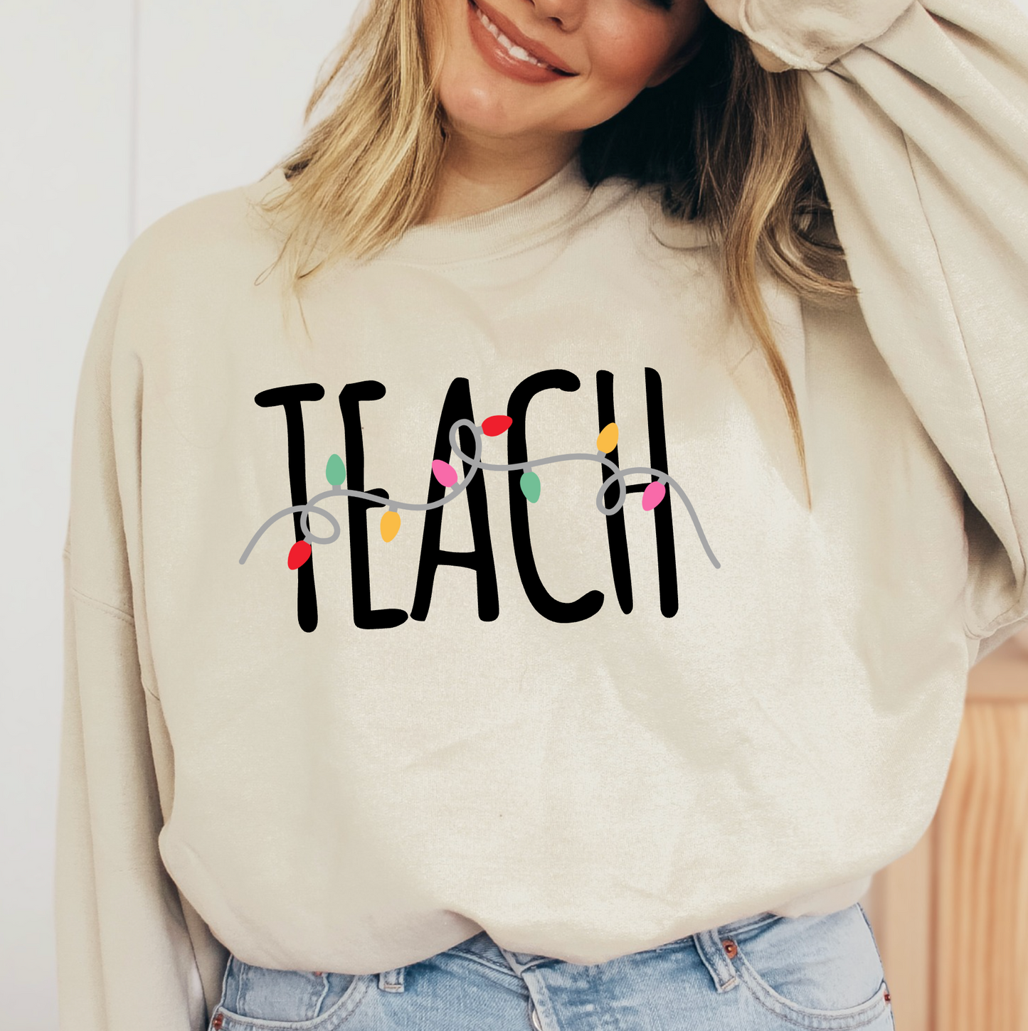 A woman wearing a white sweater with the word "TEACH" printed on it.