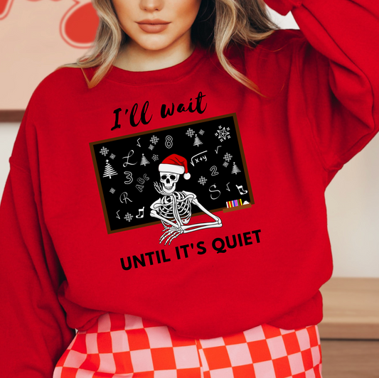 A woman wearing a red sweater with a graphic design of a skeleton wearing a Santa hat and the text "I'll wait UNTIL IT'S QUIET" printed on it.