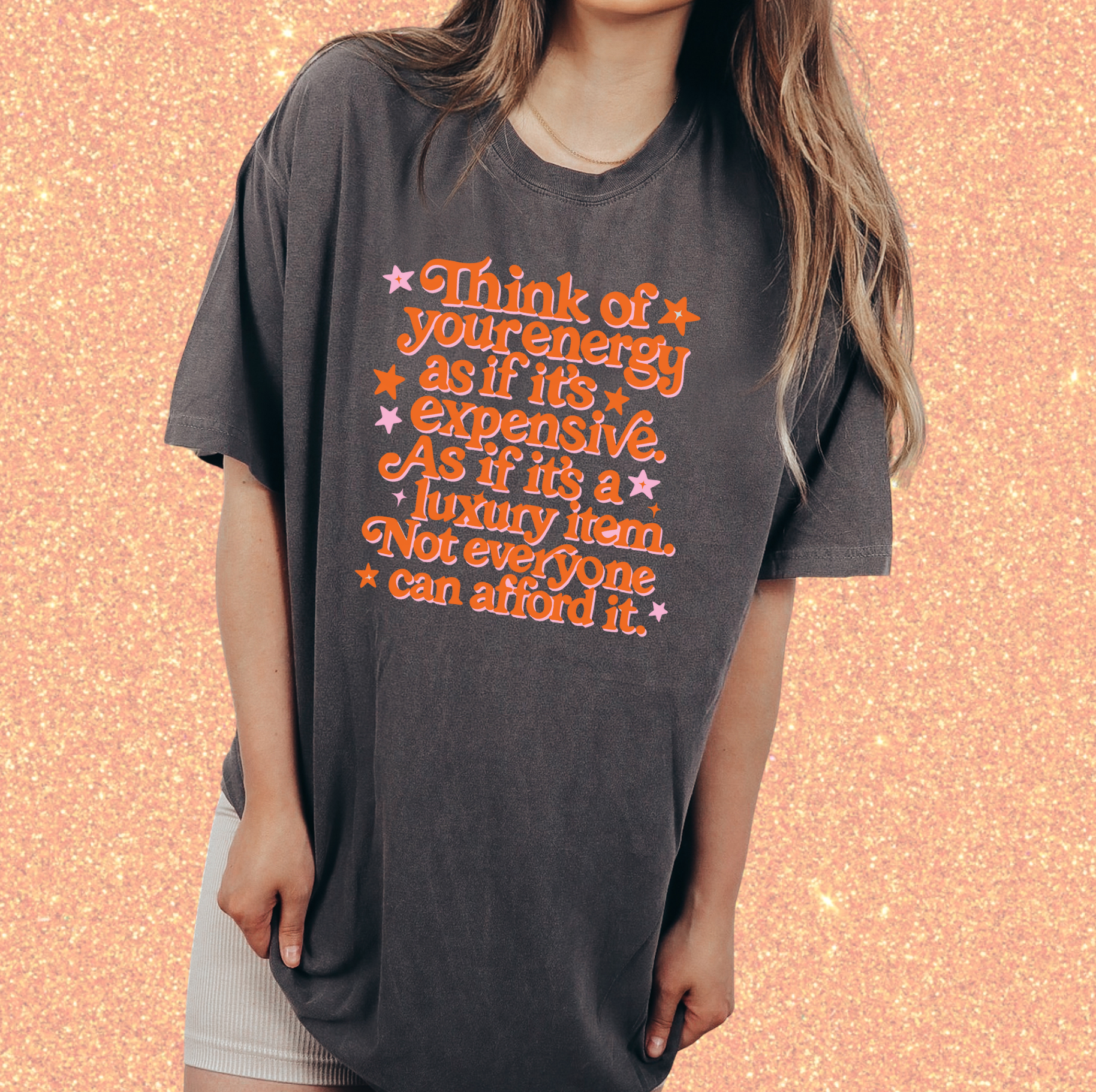 A woman wearing a gray t-shirt with a printed message about energy and luxury.